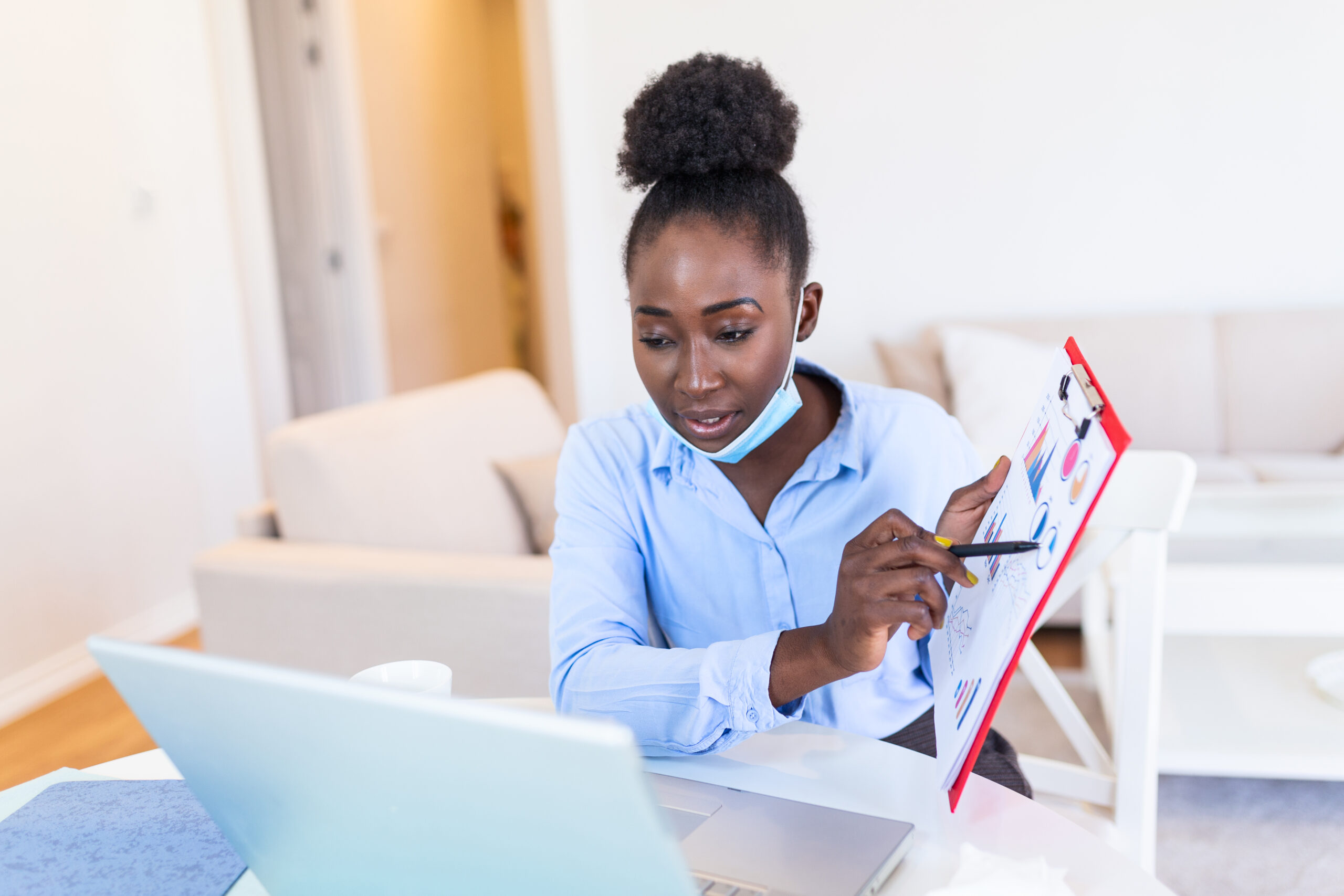 African american businesswoman having video conference while in quarantine during COVID-19 pandemic. Analyzing stock market chart and key performance indicators via video call