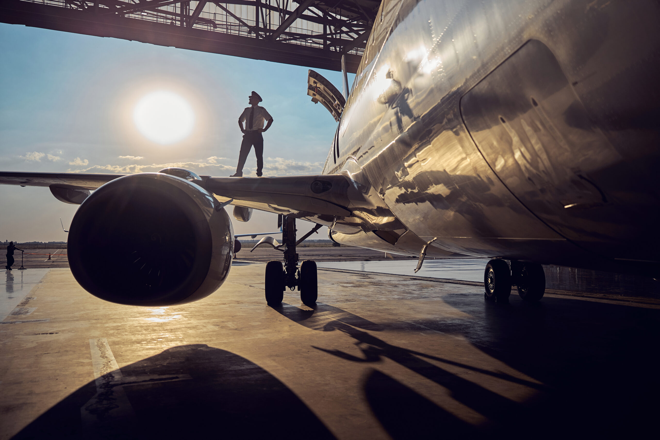 Close up image of engine of big passenger airplane in the aviation hangar while pilot standing on wing